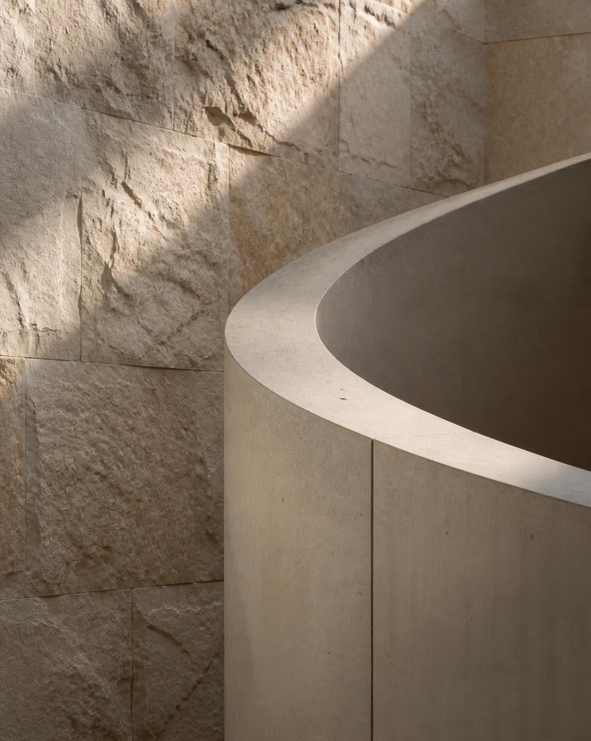 Daylight falling across a limestone and concrete interior detail